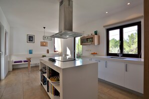 Eine moderne Küche mit Kochinsel, weißen Schränken und einem großen Fenster für natürliches Licht.