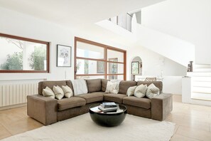 A modern living room with a sectional sofa, a coffee table, and large windows.