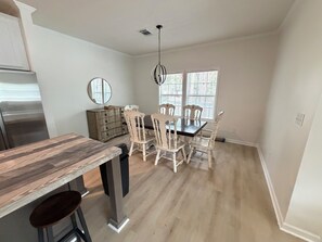 A dining area with a wooden table and chairs, a chandelier, and a window with blinds. - Nonna's Cottage,Spacious 3-bedroom Stand alone house,cart and landtrans included (Daufuskie Island)