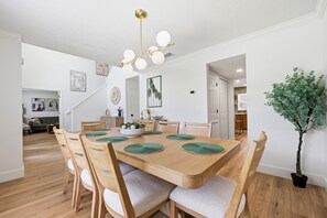 A dining area with a wooden table, chairs, and a ceiling light fixture. - 7BR Heated Pool | Game Room + Private Suite (Palm Coast)