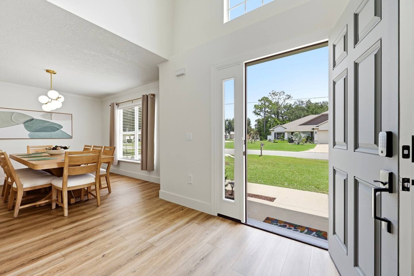 A modern interior with a dining area, a sliding glass door leading to a backyard, and a security keypad on the door.