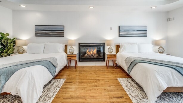 Ein Hotelzimmer mit zwei Betten, einem Kamin und Kunstwerken an den Wänden.