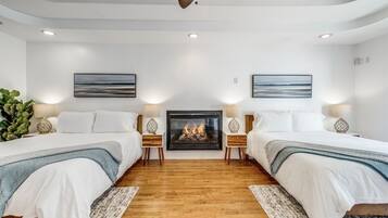 A hotel room with two beds, a fireplace, and artwork on the walls.