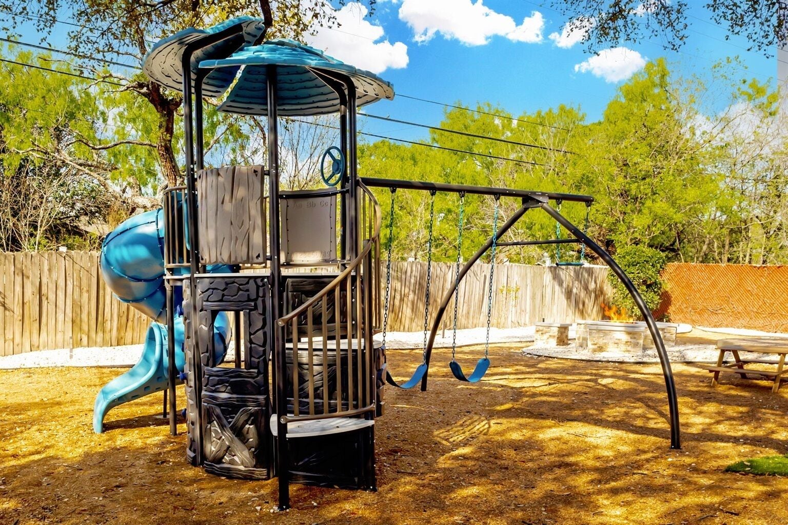 Un parque infantil con tobogán, columpios y una estructura para escalar.