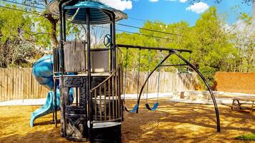 Un parque infantil con tobogán, columpios y una estructura para escalar.