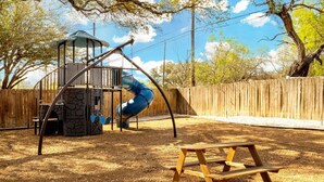 Ein Spielplatz mit Rutsche, Schaukeln und einer Holzbank.