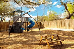 Un parque infantil con tobogán, columpios y un banco de madera.