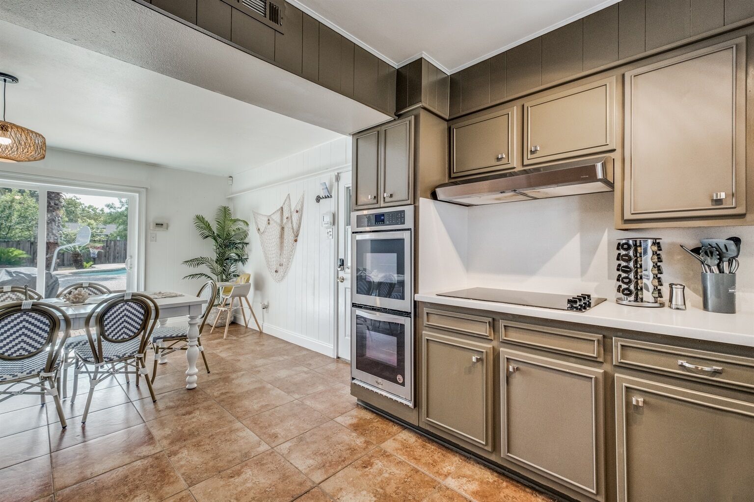 A kitchen with wooden cabinets, a countertop, and a dining area with chairs and a table.