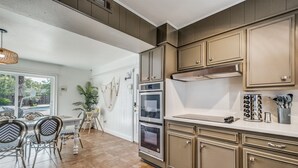 Eine Küche mit Holzschränken, einer Arbeitsplatte und einem Essbereich mit Stühlen und einem Tisch.