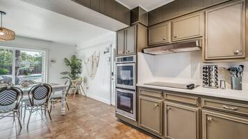A kitchen with wooden cabinets, a countertop, and a dining area with chairs and a table.