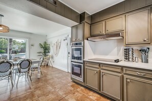 Una cocina con armarios de madera, una encimera y un comedor con sillas y una mesa.