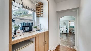 A narrow kitchen with a coffee machine, a sink, and a wine rack.