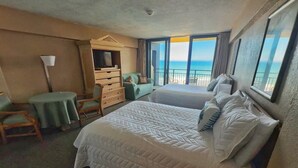Een hotelkamer met een groot bed, een bureau, een stoel en uitzicht op de oceaan.
