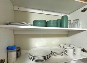 A kitchen shelf with stacked plates, bowls, and mugs. - NEW Amazing Ocean Front Studio-Up to 4 Guests! (Daytona Beach Shores)