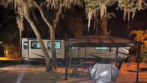 Een camping met een overdekte paviljoen, een eettafel en een barbecue.