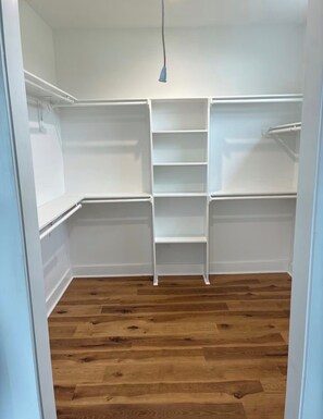 Ein begehbarer Kleiderschrank mit weißen Regalen und einer Deckenleuchte.