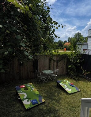 A backyard with a wooden fence, a round table with chairs, and two green play mats. - Modern Home Near Houston Heights/Airport/Downtown

2 Miles from Best Night Life (Houston)