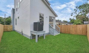 Ein Wohnhaus mit überdachter Veranda, Holzzaun und gepflegtem Rasen.
