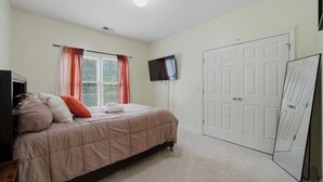 A bedroom with a bed, a TV, a wardrobe, and a door. - Modern 4BR Retreat Near ATL Airport & Attractions (Atlanta)