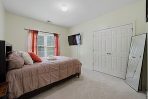 Un dormitorio con cama, televisor, armario y puerta.
