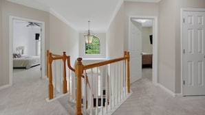 A hallway with a wooden staircase, a bedroom with a bed, and a bathroom with a toilet. - Modern 4BR Retreat Near ATL Airport & Attractions (Atlanta)