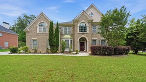 A two-story house with a symmetrical facade, a central entrance with a door, and a small porch. - Modern 4BR Retreat Near ATL Airport & Attractions (Atlanta)