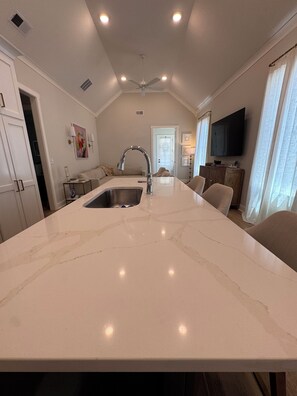Une cuisine dotée d’un îlot central, d’un évier intégré et d’un ventilateur de plafond.