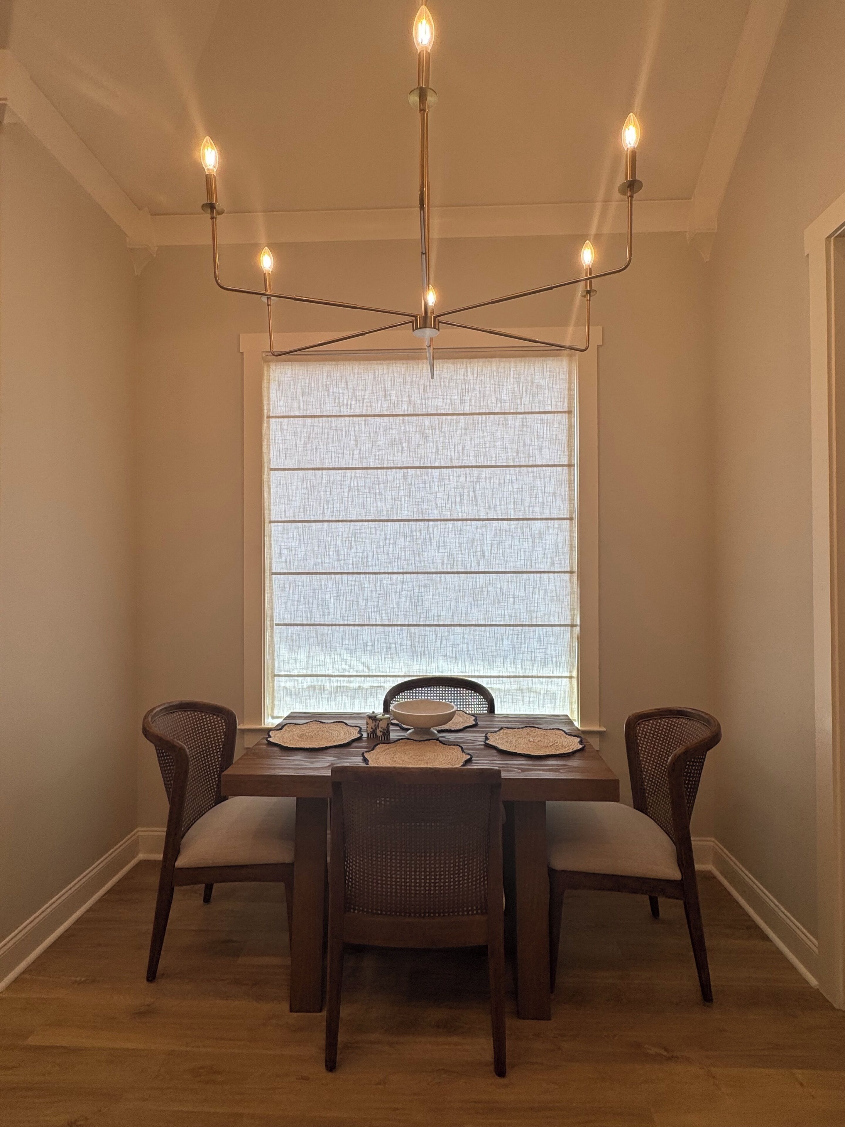 Zona pranzo con tavolo apparecchiato per quattro, circondato da sedie, illuminato da un lampadario moderno.