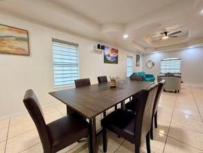 A dining area with a long table, chairs, and a ceiling fan.