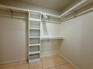 A walk-in closet with a built-in shelving unit and a hanging rod.