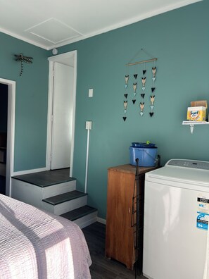 Un espace dédié à la lessive, comprenant un lave-linge, un meuble en bois et un seau bleu.