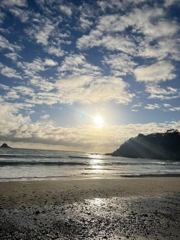 Une plage avec des vagues, un ciel dégagé et le soleil se couchant ou se levant.