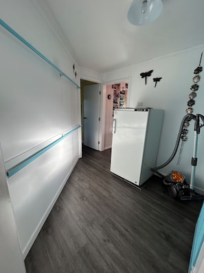 Une cuisine avec un réfrigérateur blanc, un aspirateur et un climatiseur fixé au mur.