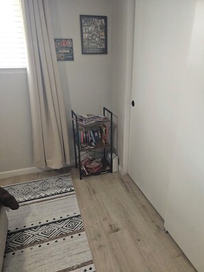 Un rincón de una habitación con una estantería, una alfombra estampada y una puerta.