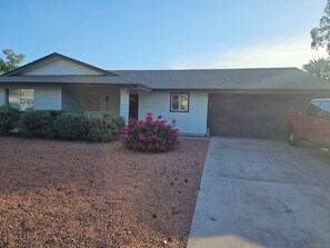 Ein Bungalow mit Garage, Auffahrt und Kiesgrundstück.