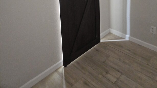 Una habitación con puerta corrediza de estilo rústico, paredes de tonos claros y piso de madera.
