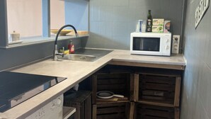 Een kleine keuken met een wasmachine, een magnetron en een spoelbak.
