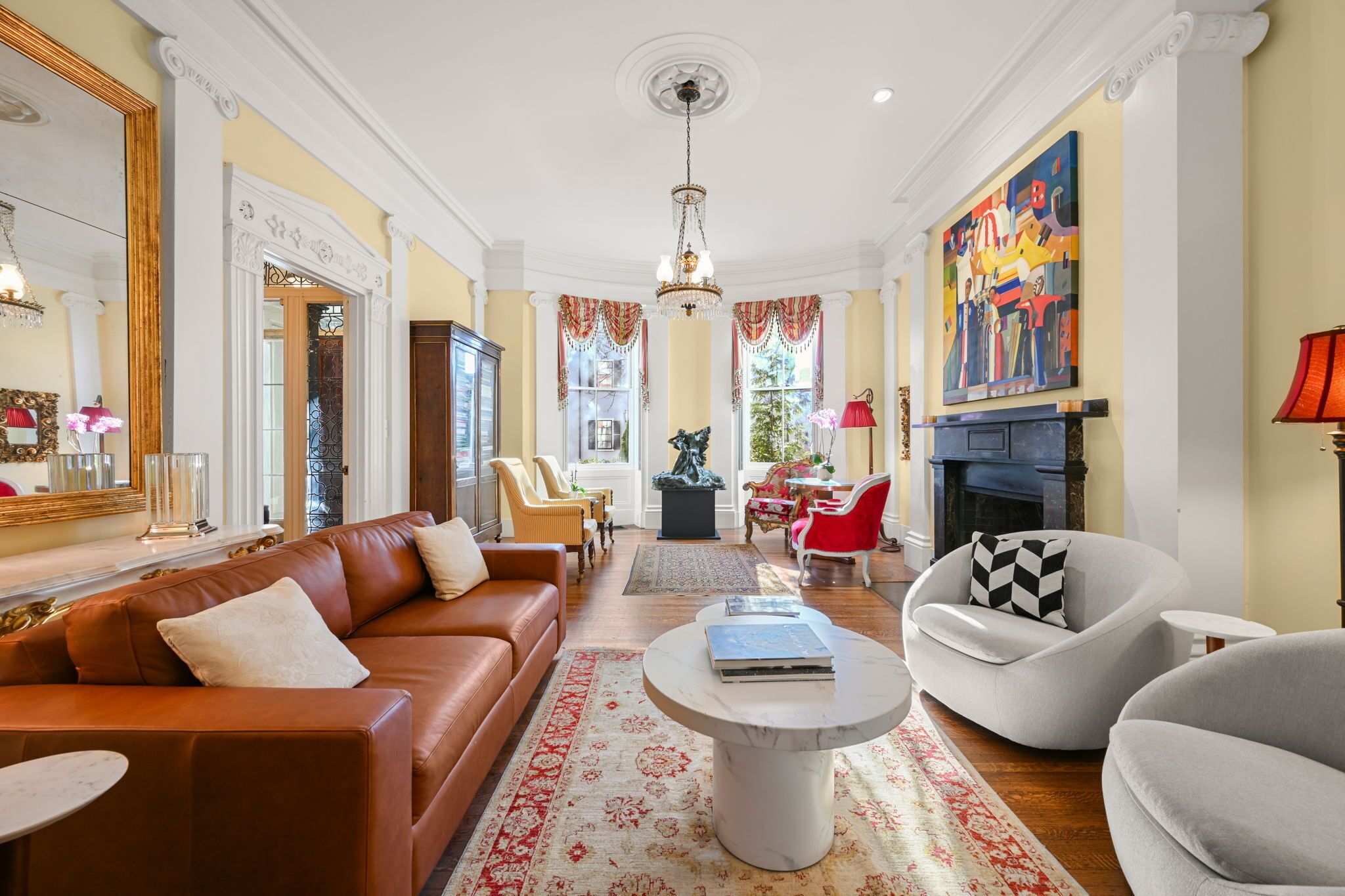 A spacious living room with a brown leather sofa, a round coffee table, and a fireplace.
