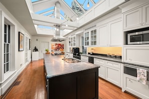 A modern kitchen with white cabinetry, a central island, and a skylight.