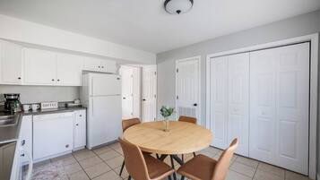 A modern kitchen with white cabinets, a round wooden table, and brown chairs.