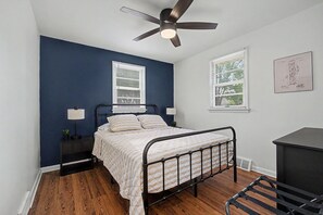 A bedroom with a bed, two bedside tables, a ceiling fan, and two windows with blinds. - Remodeled home by Air Force Base, Wright State University and Nutter Center (Fairborn)