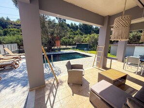 A covered outdoor area with a pool, lounge chairs, and wicker furniture. - Villa Fountain (Pool, Garden, BBQ, Starlink, Wood House) (Afantou)