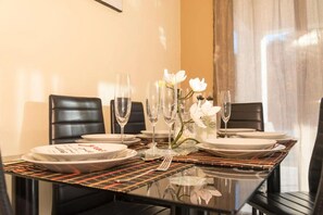 A dining table set for four with plates, cutlery, and glasses, accompanied by a vase of white flowers. - Villa Fountain (Pool, Garden, BBQ, Starlink, Wood House) (Afantou)