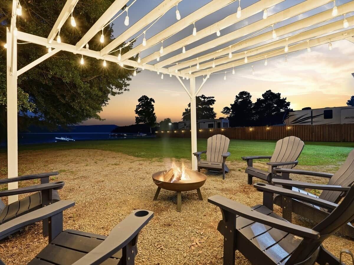 An outdoor patio with Adirondack chairs, a fire pit, and string lights.