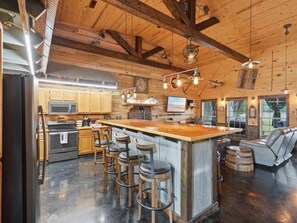 A kitchen with a bar area, wooden bar stools, and a large island.