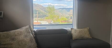 A living room with a sofa and a window overlooking a residential area.
