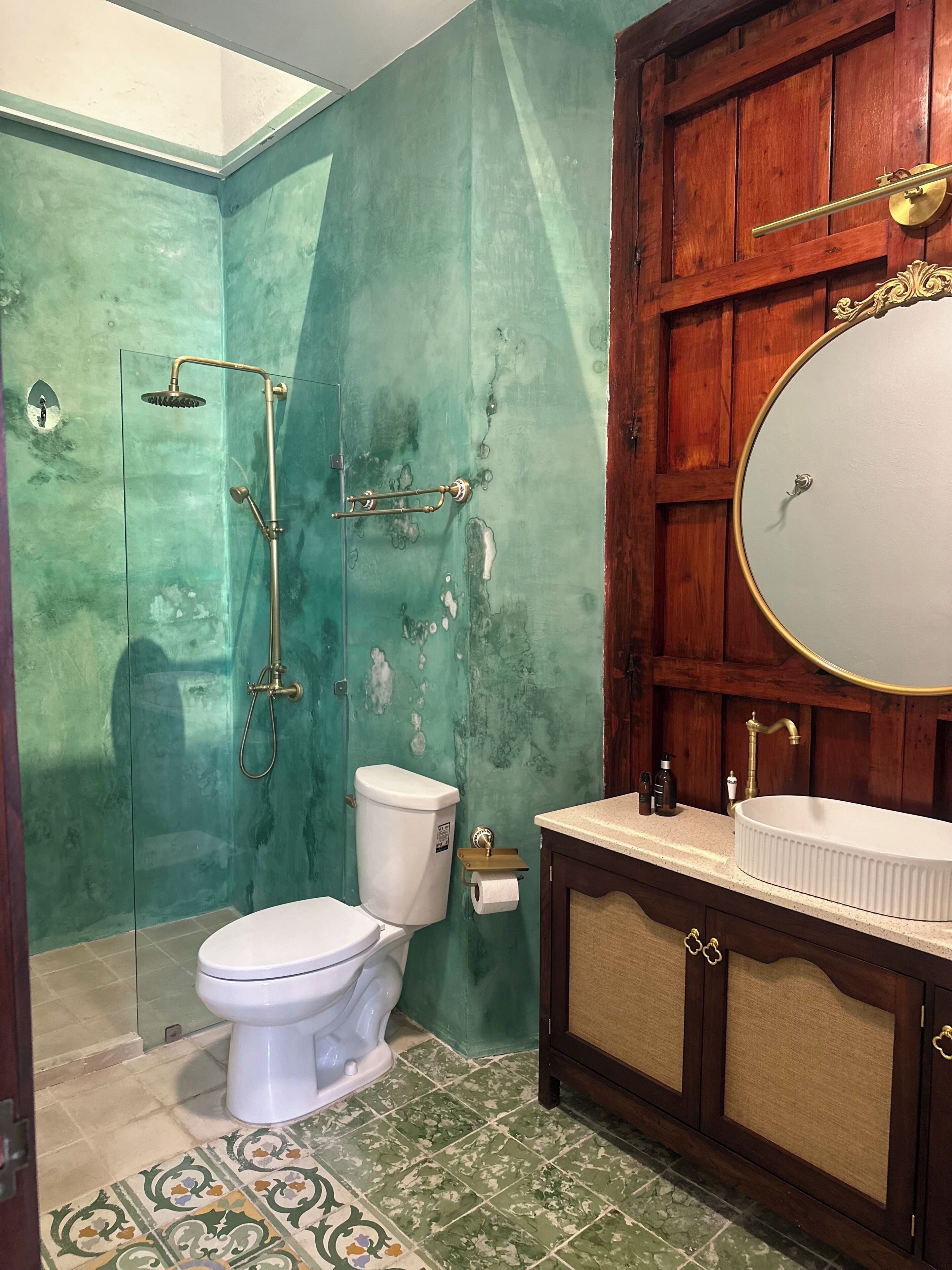 A bathroom with a toilet, shower, vanity with a mirror, and a sink.