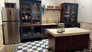 Eine Küche mit Kühlschrank, Schränken, einer Spüle und einem Schachbrettmuster Boden.