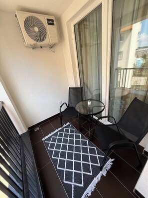 A balcony with a black and white patterned rug, two black chairs, a small round table, and a ceiling fan. - Daky home near AirPort,tram and City center (Sarajevo)