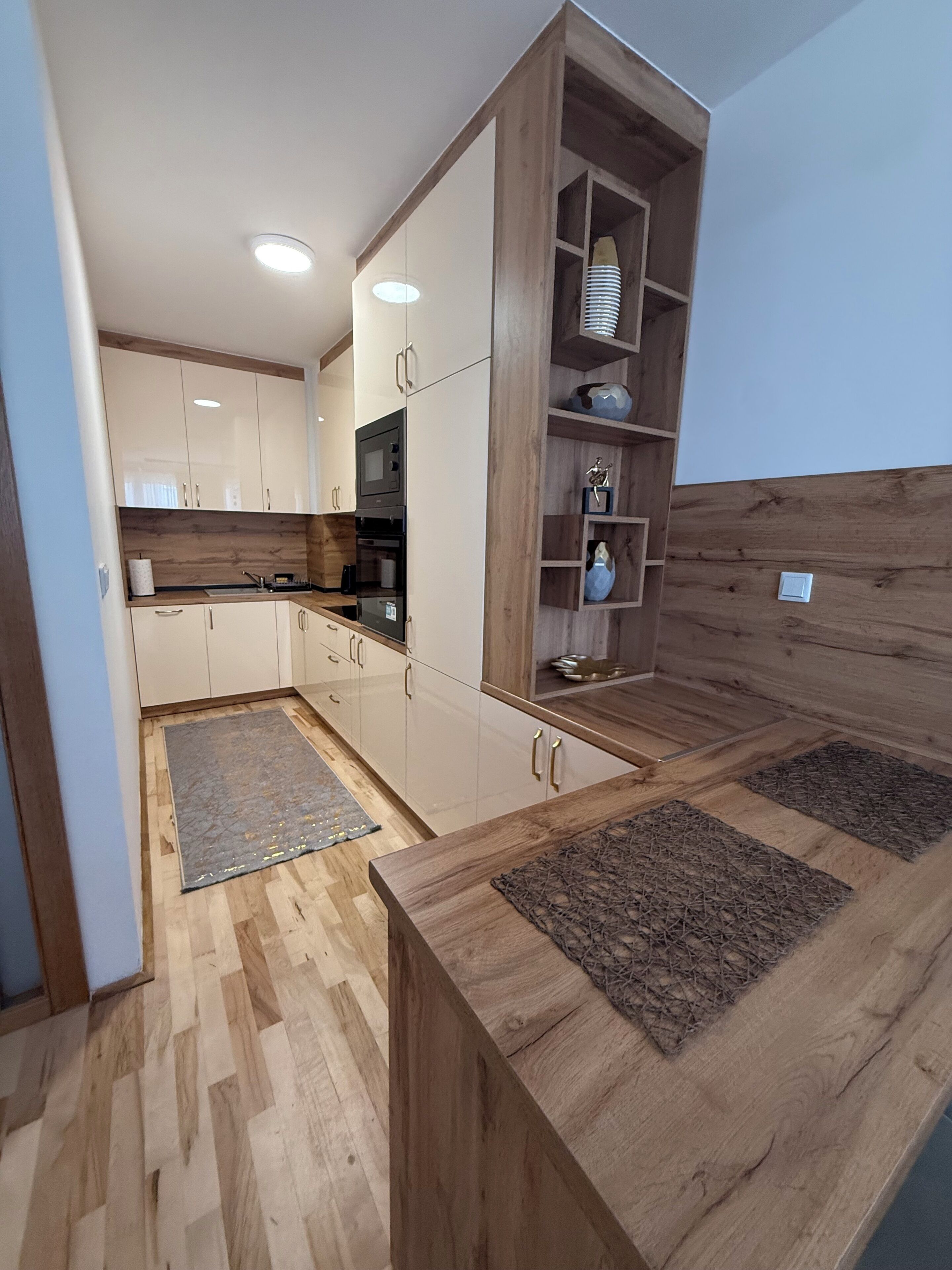 A modern kitchen with wooden cabinets, a built-in oven, and a wooden countertop.